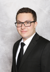 A man wearing glasses, smiling. 